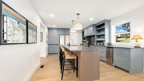 Een moderne keuken met een centraal eiland, barstoelen en uitzicht naar buiten.