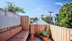 Une terrasse en bois avec un banc intégré et des plantes en pot.