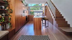 Une cuisine moderne avec des meubles en bois, un îlot central et un escalier menant à un niveau supérieur.