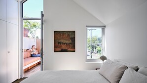 Une chambre à coucher avec un lit, un tableau et une fenêtre donnant sur l’extérieur.
