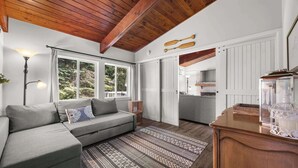 Un salon chaleureux avec un canapé, un tapis à motifs et un plafond en bois.