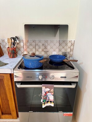 A kitchen with a stove, pots, and a hanging towel. - Cozy 2-bedroom house in delightful La Fortuna with AC (La fortuna)