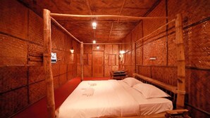 A wooden room with a bed, a small table, and a door.