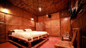A wooden room with a bed, a small table, and a chair.