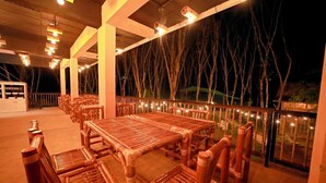 An outdoor dining area with bamboo furniture and string lights.