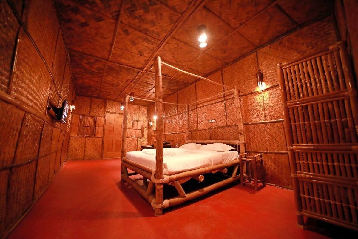 A four-poster bed in a room with wooden walls and a red carpet.