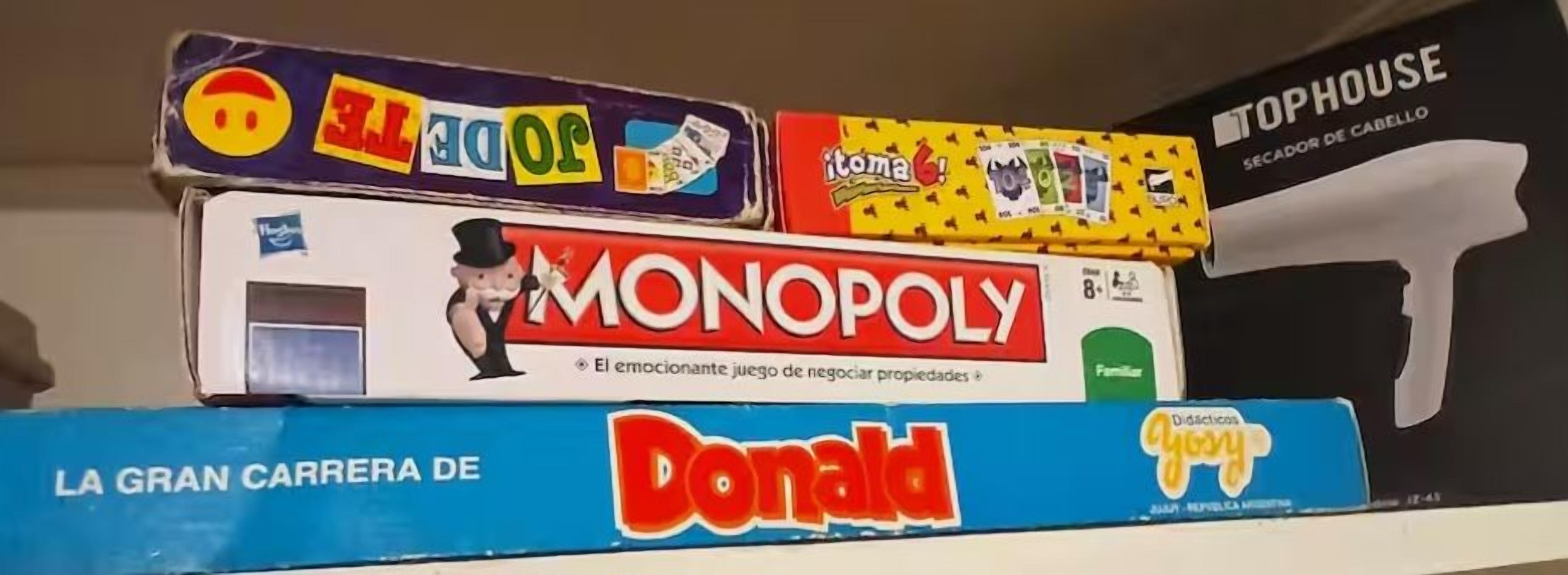 A stack of board games including Monopoly, La Gran Carrera de Donald, and Tophouse.