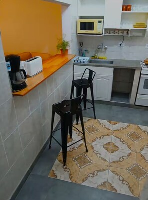 A compact kitchen with a microwave, toaster, sink, and two bar stools. - Serena Suipacha  (Mendoza)