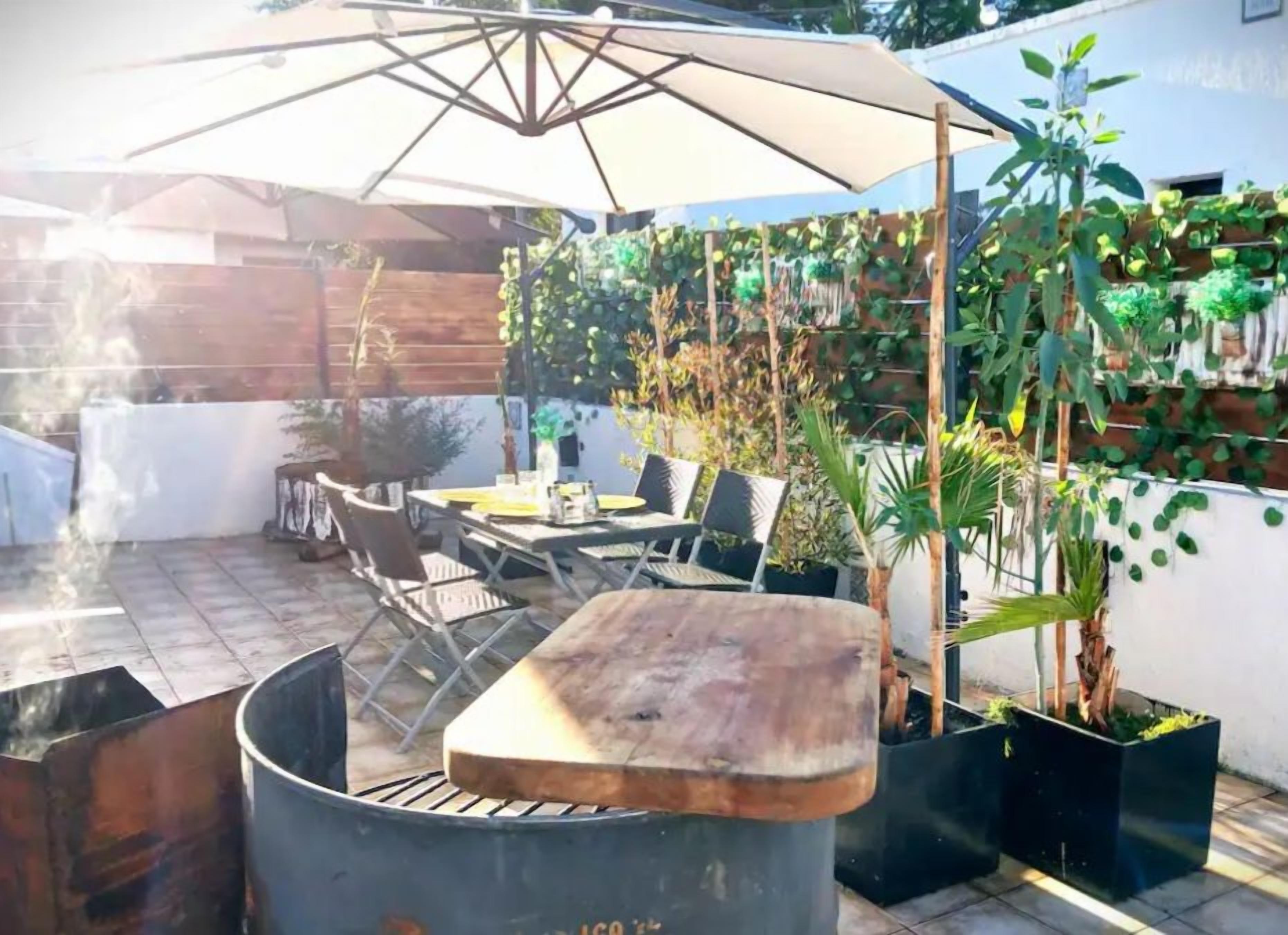 Un patio exterior con una parrilla, zona de estar y plantas en macetas.