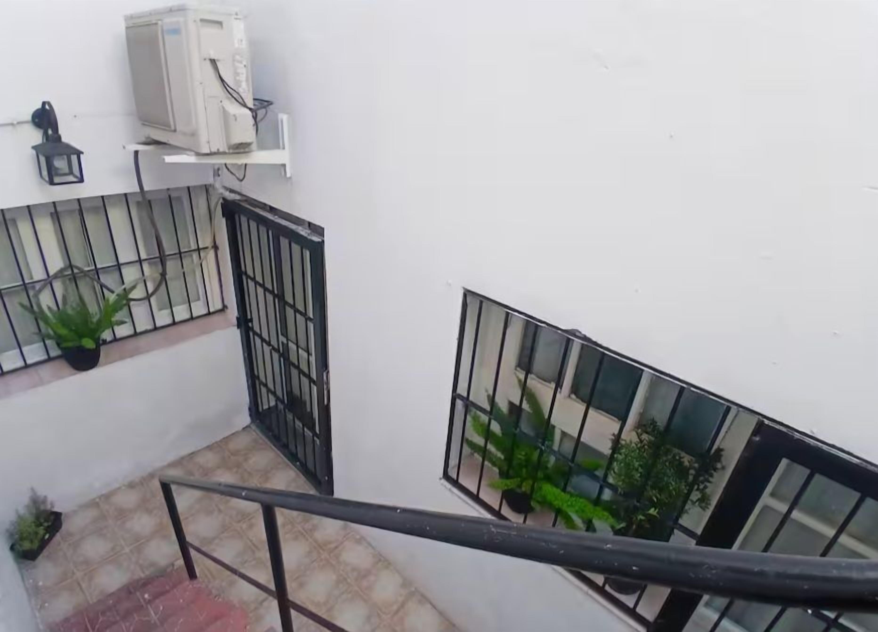 A staircase with a metal railing, a potted plant, and a white wall with a window.