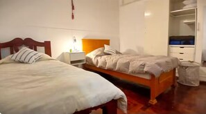 Un dormitorio con dos camas, una mesita de noche, un armario y un cubo de basura.