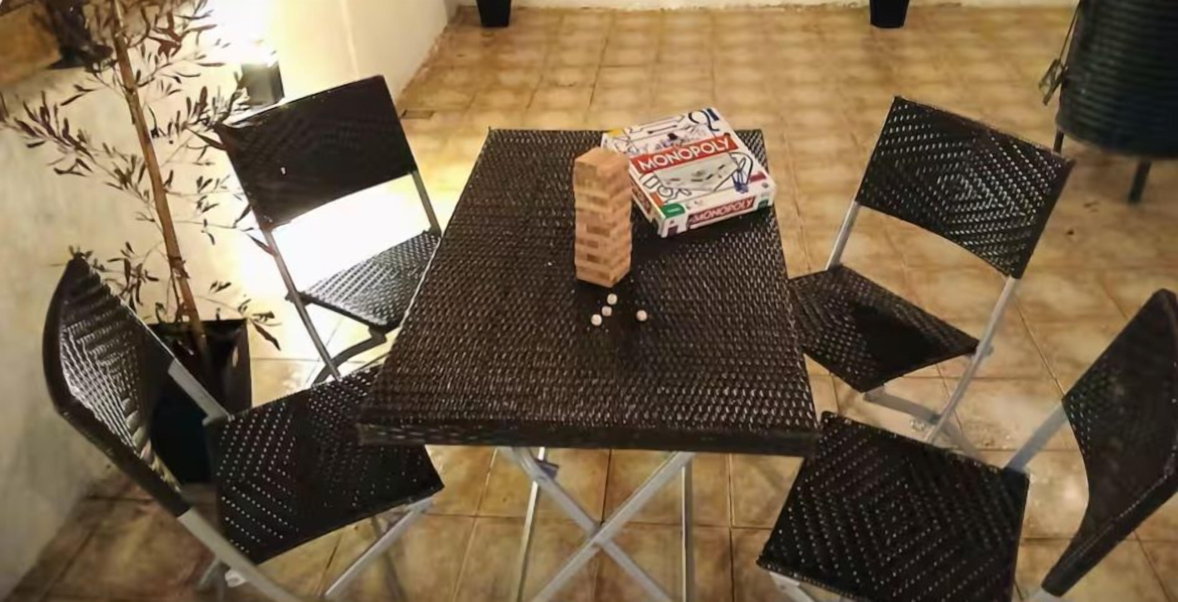 A table with a Monopoly game box and a brick, surrounded by four chairs.