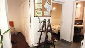 Un pasillo con un tablón de anuncios, un caballete de madera y una planta en maceta.