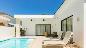 Un espace aménagé au bord de la piscine, comprenant des chaises longues, un barbecue et un coin salon abrité.