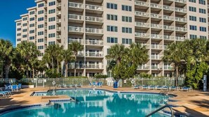 A hotel with a swimming pool surrounded by palm trees and blue chairs. - Summit Blue at TOPS'L , Gulf Views, Beach & Pool (Miramar Beach)