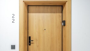 Una porta in legno con una tastiera numerica, una maniglia e un piccolo foro al centro.