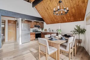 Eine moderne Küche mit Holzschränken, einem Edelstahlkühlschrank und einem Essbereich mit Holztisch und Stühlen.