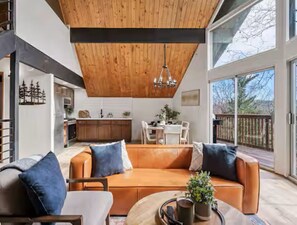 Ein modernes Wohnzimmer mit Holzbalkendecke, einer Couch und einem Couchtisch.