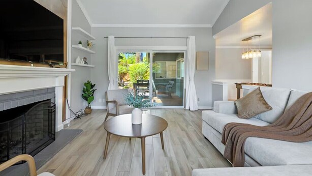 Una sala de estar moderna con chimenea, un sofá, una mesa de centro y vistas al exterior a través de un ventanal.