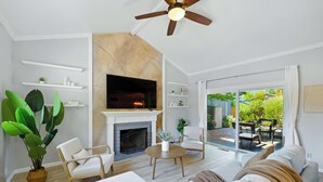 Una sala de estar moderna con chimenea, asientos cómodos y un gran ventanal que ofrece vistas al exterior.