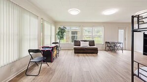 A spacious living room with a sofa, a small table, and a gaming table. - The Rose 1 (Broussard)