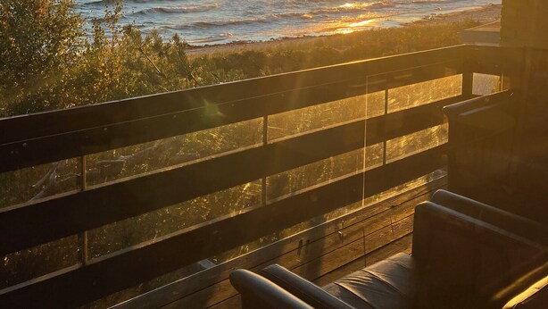 Ett trädäck med utsikt över havet och en vacker solnedgång.