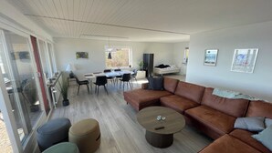 Ett modernt vardagsrum med en matplats, en soffa, pallar och ett runt soffbord.