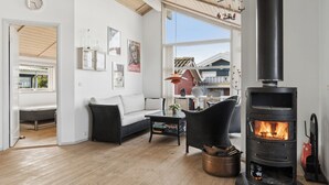 A cozy living room with a fireplace, a sofa, a coffee table, and a view of the outside. - Lovely holiday home panoramic view over the sea (Slagelse)