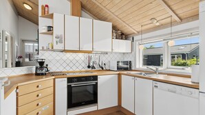 A modern kitchen with wooden cabinets, a built-in oven, and a dishwasher. - Lovely holiday home panoramic view over the sea (Slagelse)
