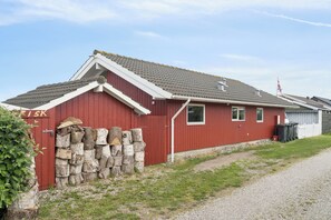 A red building with a sloped roof, a stone wall, and a gravel path. - Lovely holiday home panoramic view over the sea (Slagelse)