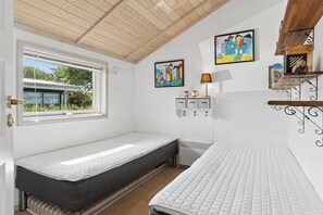 A room with two beds, a window, a radiator, and wall art. - Lovely holiday home panoramic view over the sea (Slagelse)