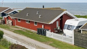 A red house with a white fence, a white RV, and a view of the sea and a bridge. - Lovely holiday home panoramic view over the sea (Slagelse)