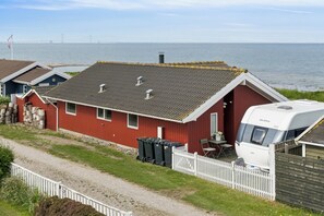 A red house with a white fence, a white RV, and a view of the sea and a bridge. - Lovely holiday home panoramic view over the sea (Slagelse)