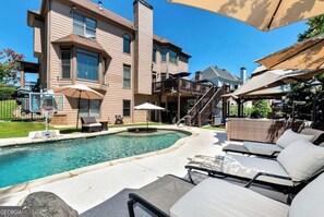 Propiedad residencial con piscina, mobiliario exterior y una escalera que conduce a un nivel superior.