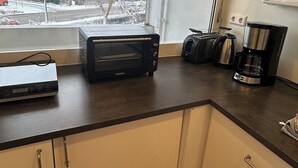 A kitchen with a window, a toaster, a coffee maker, and a microwave. - FeWo am Deich 2, modern apartment with balcony and elevator (Bremerhaven)