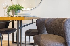 Un coin repas avec une table dressée pour deux personnes, une plante en pot et un verre à vin.