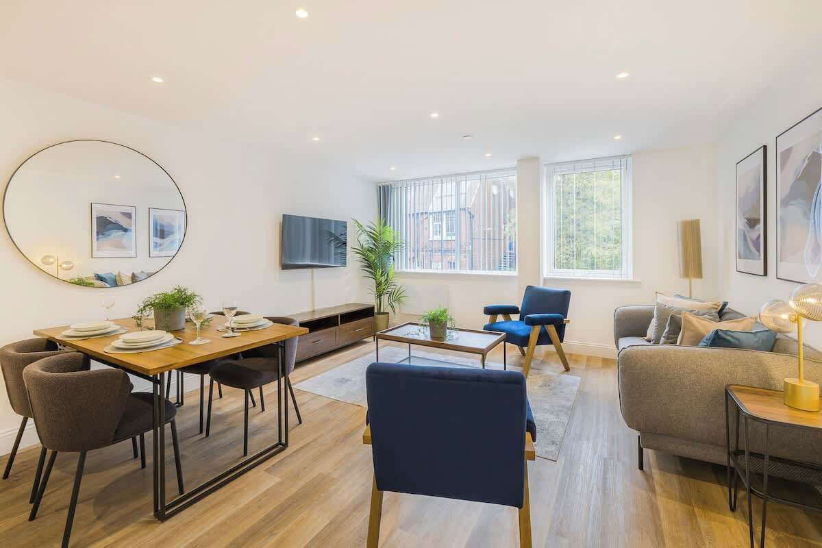 Een moderne woonkamer met een eethoek, een bank, een televisie en een groot raam.
