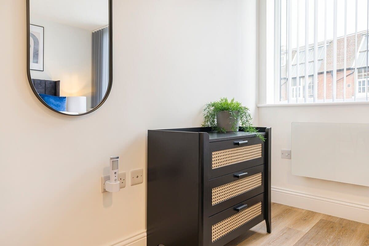A modern room with a black cabinet, a mirror, and a window with a view of buildings.