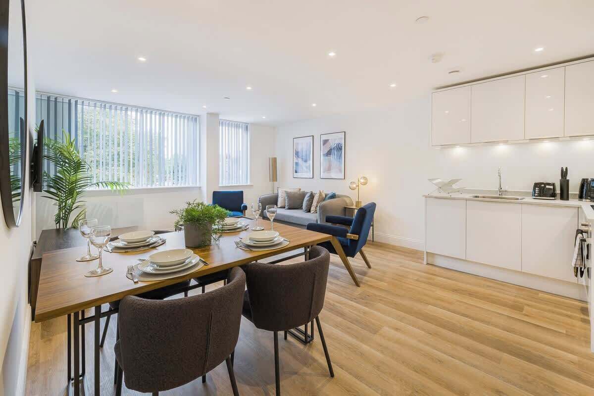 A modern living space with a dining area, a sofa, and a kitchen.