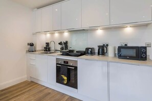 Eine moderne Küche mit weißen Schränken, einem Backofen, einer Mikrowelle und einer Kaffeemaschine.