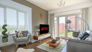 Ett modernt vardagsrum med en tv, en soffa, ett soffbord och utsikt över omgivningarna.