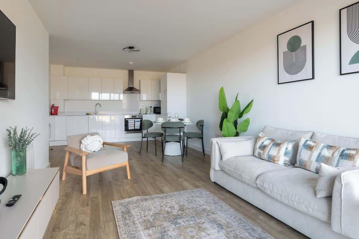 En moderne stue med sofa, sofabord og et spiseområde med stole.