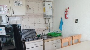 A compact kitchen with white cabinets, a stove, a sink, and a wooden table. - House in el quisco (El Quisco)