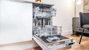 Eine moderne Küche mit Geschirrspüler, einem weißen Schrank und einem grauen Sofa.