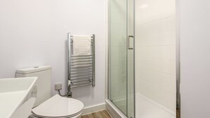Un baño moderno con cabina de ducha de vidrio, inodoro blanco y barra para toallas.