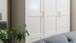 A room with a grey sofa, white wardrobe with gold handles, and a green plant. - Better Than a Hotel | Parking | Stony Stratford (Milton Keynes)