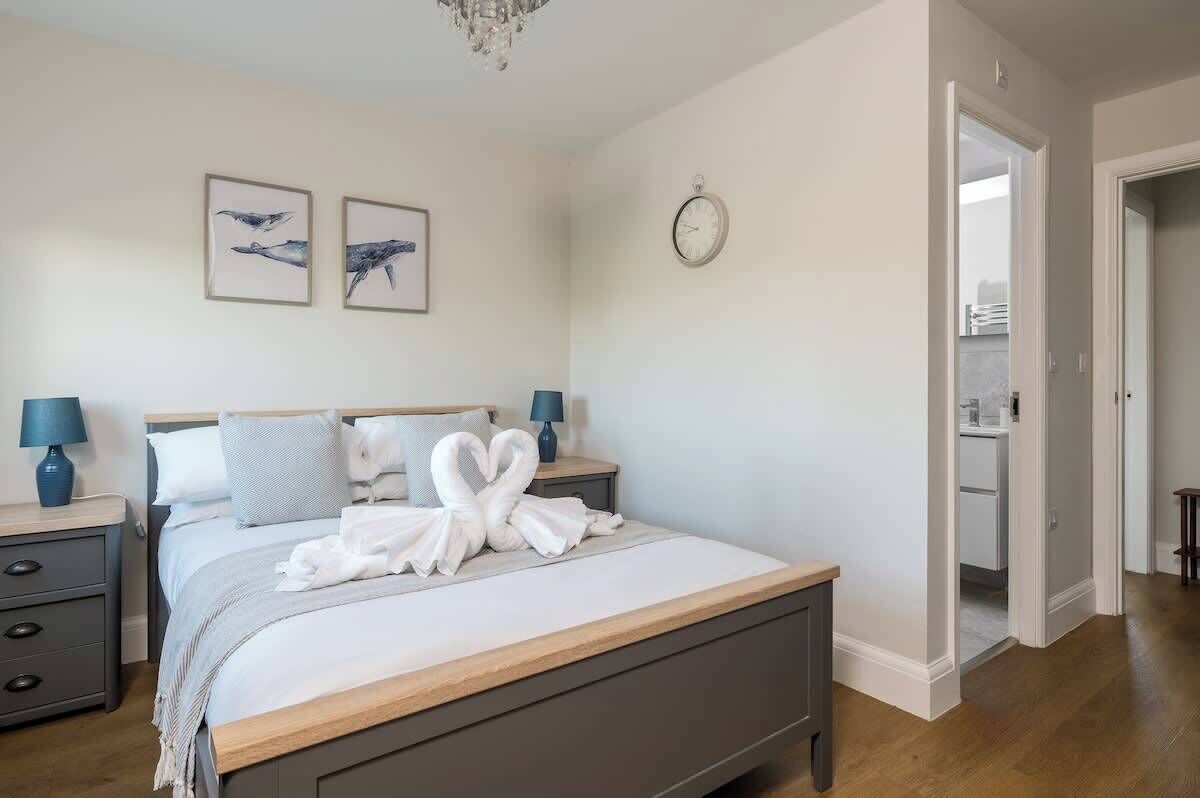 Une chambre à coucher avec un lit, deux tables de chevet, une horloge et des œuvres d’art accrochées au mur.