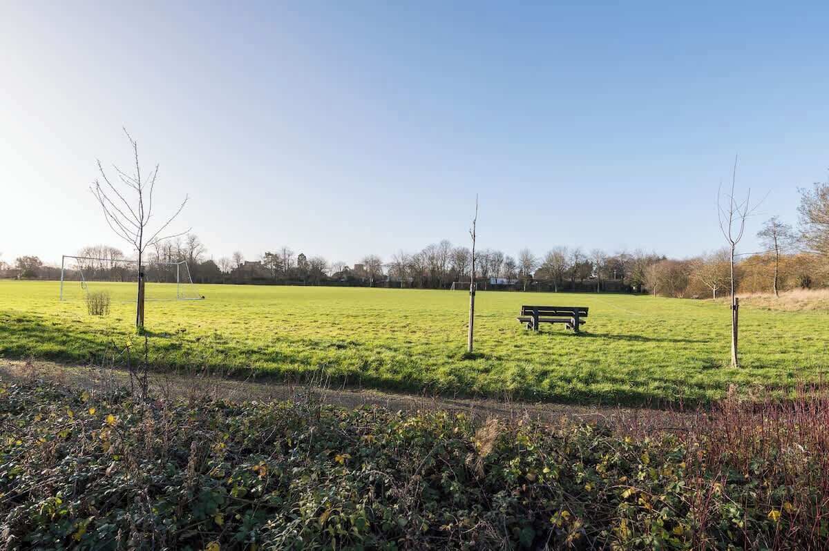 Een grasveld met een bank en een voetbaldoel in de verte.