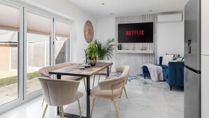 Uma sala de estar moderna com área de jantar, TV fixada na parede e uma grande janela.