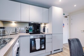 A modern kitchen with white cabinets, a built-in oven, a toaster, and a sink. - Stylish Liverpool Apartment with Parking (Liverpool)